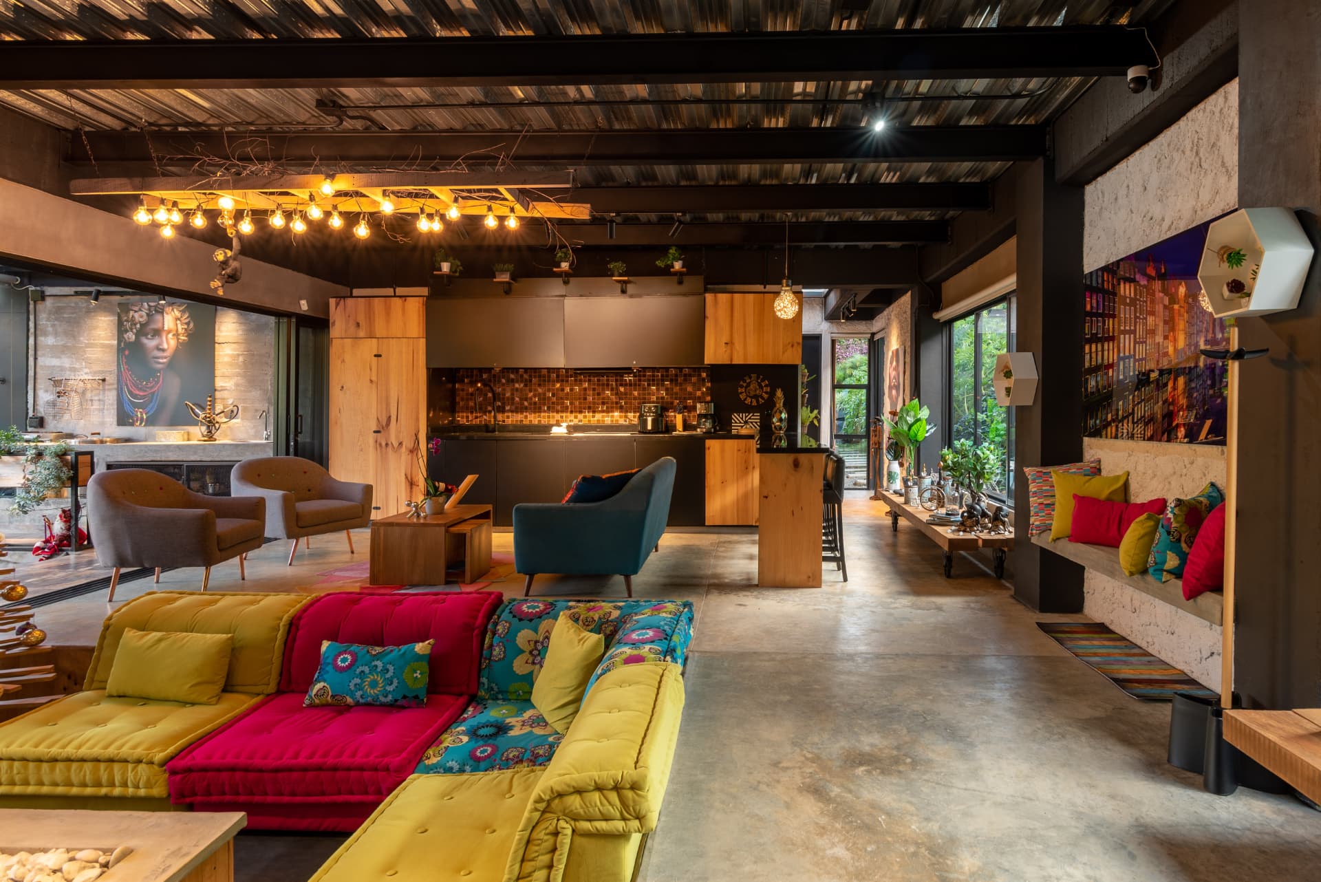 Zona social de Casa Shirley con sofás de colores y cocina abierta al fondo