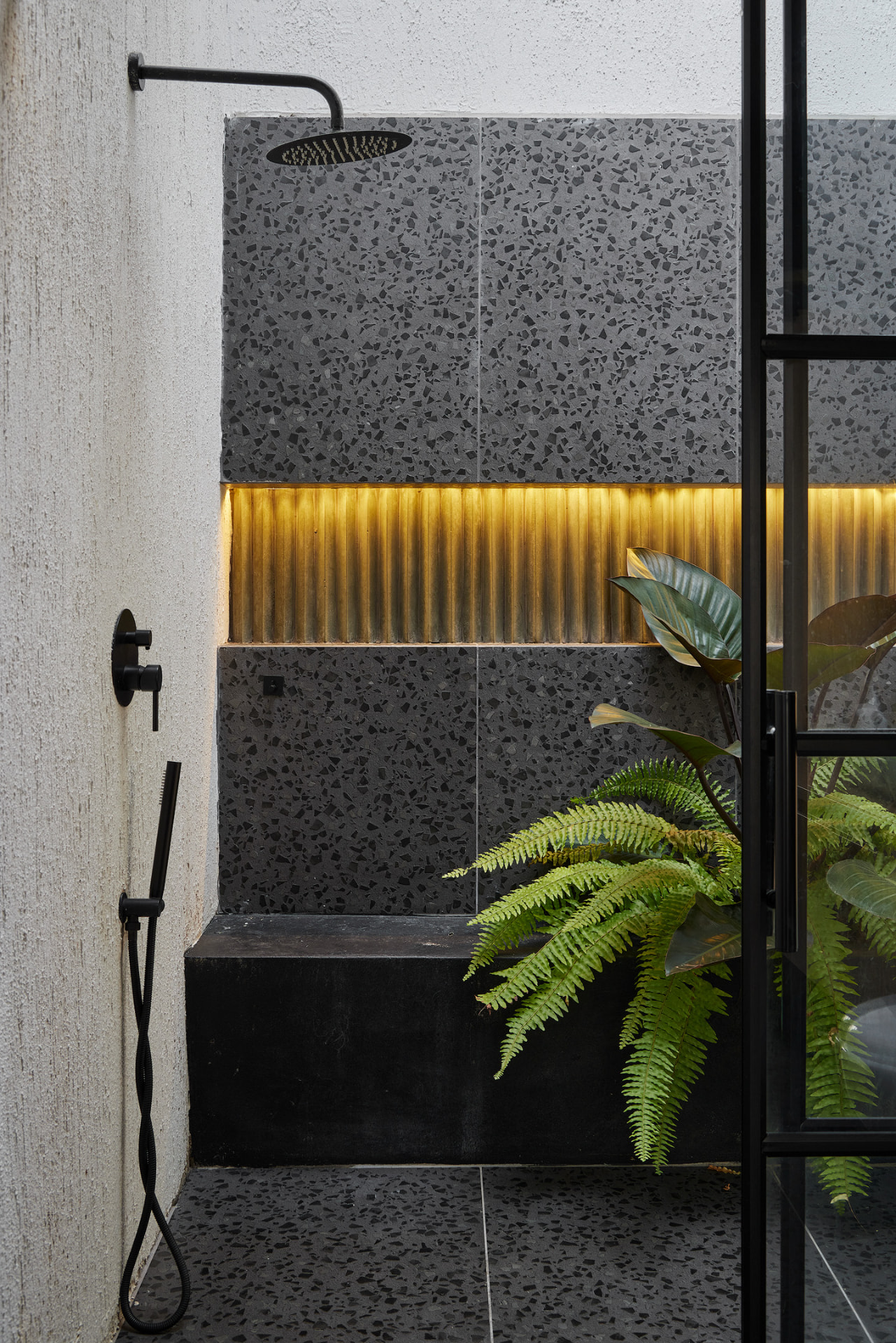 Ducha de Casa Mulata con terrazo oscuro y luz cálida integrada