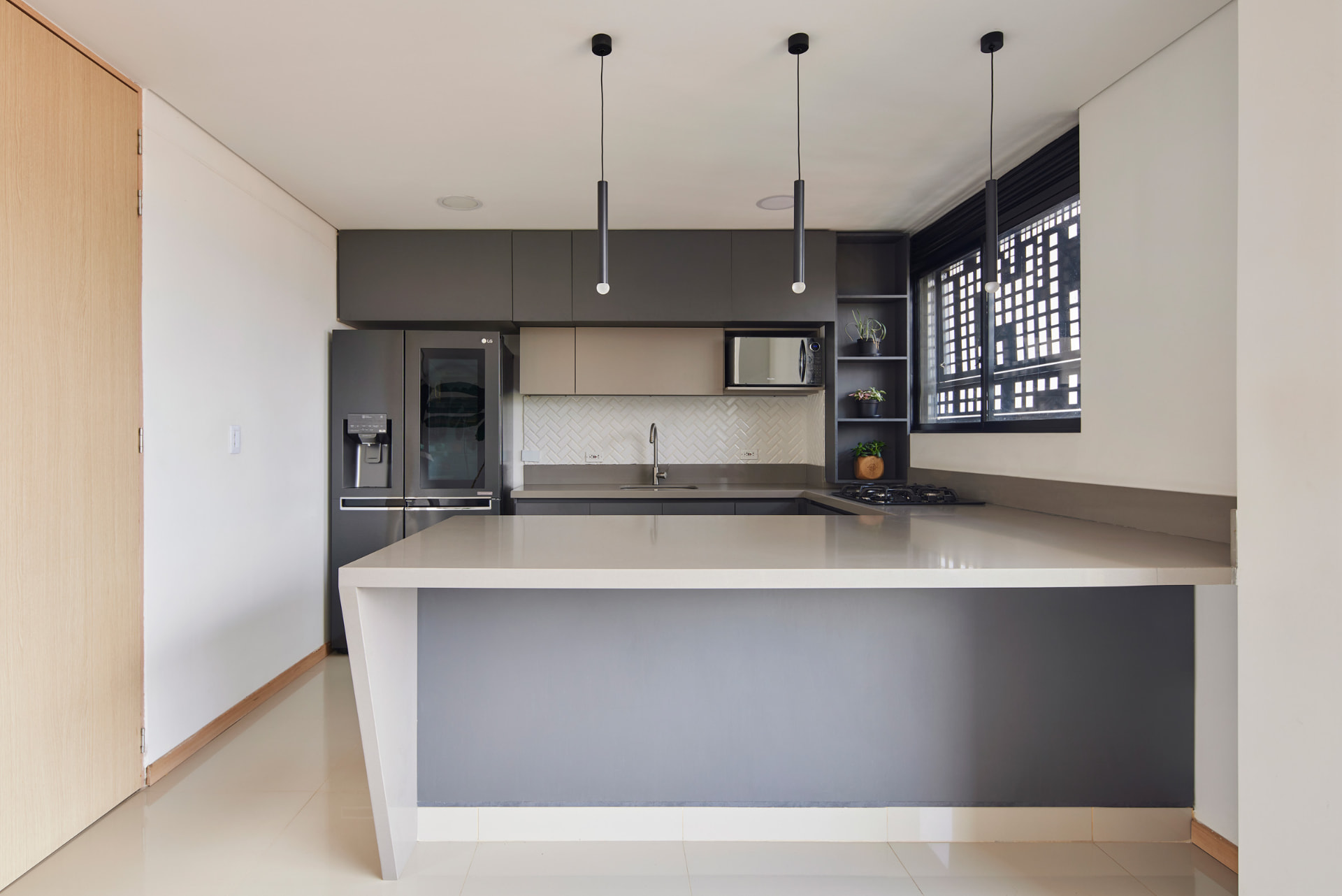 Cocina del Edificio Bianco con isla central y carpintería en tonos grises
