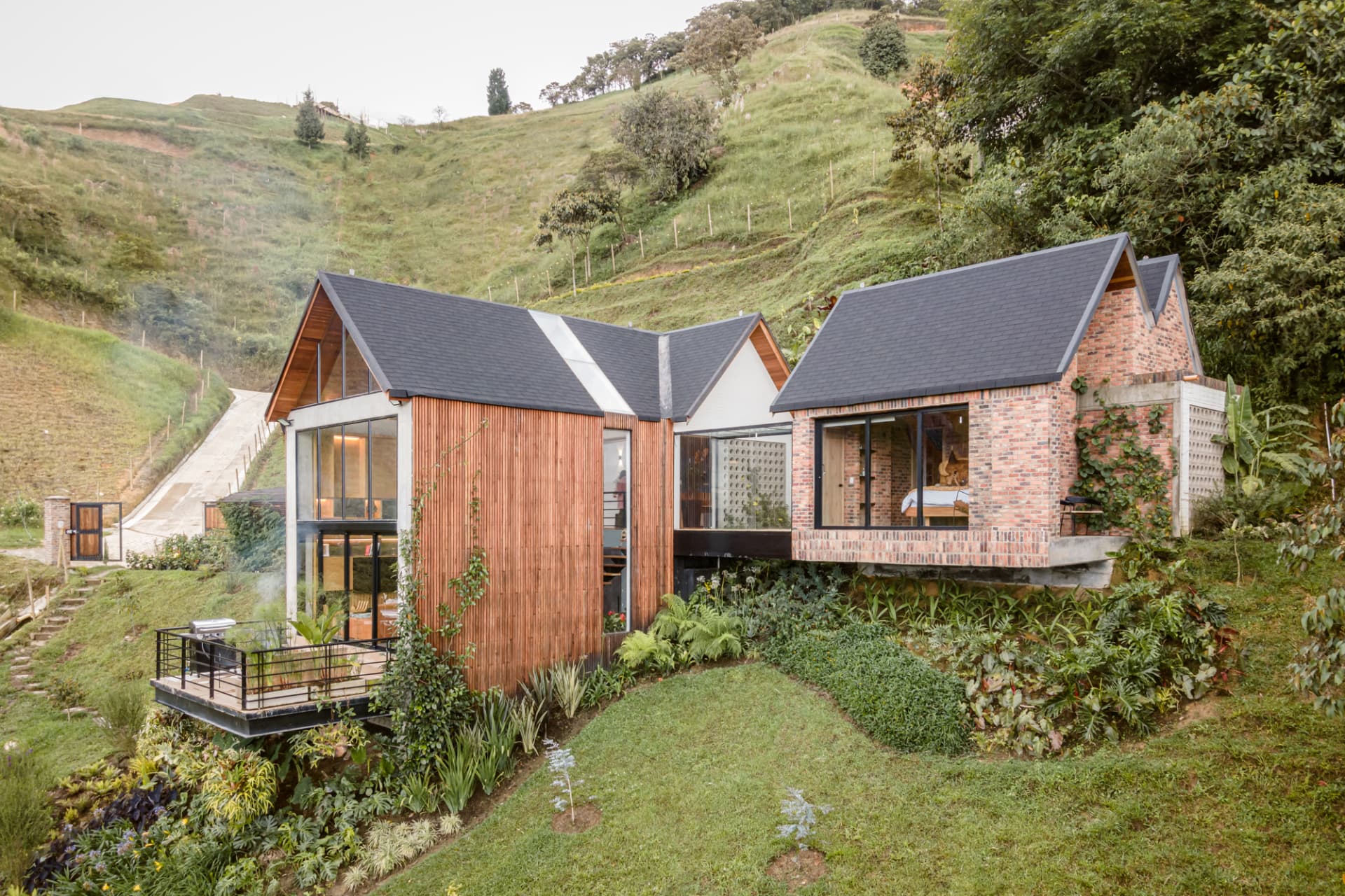 Vista diurna de Up House con techo a dos aguas y fachada de madera y ladrillo