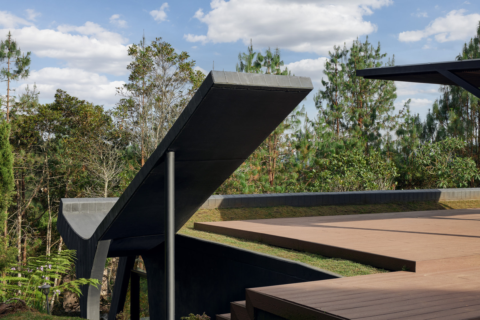 Estructura angular negra de La Madriguera sobre el deck de madera