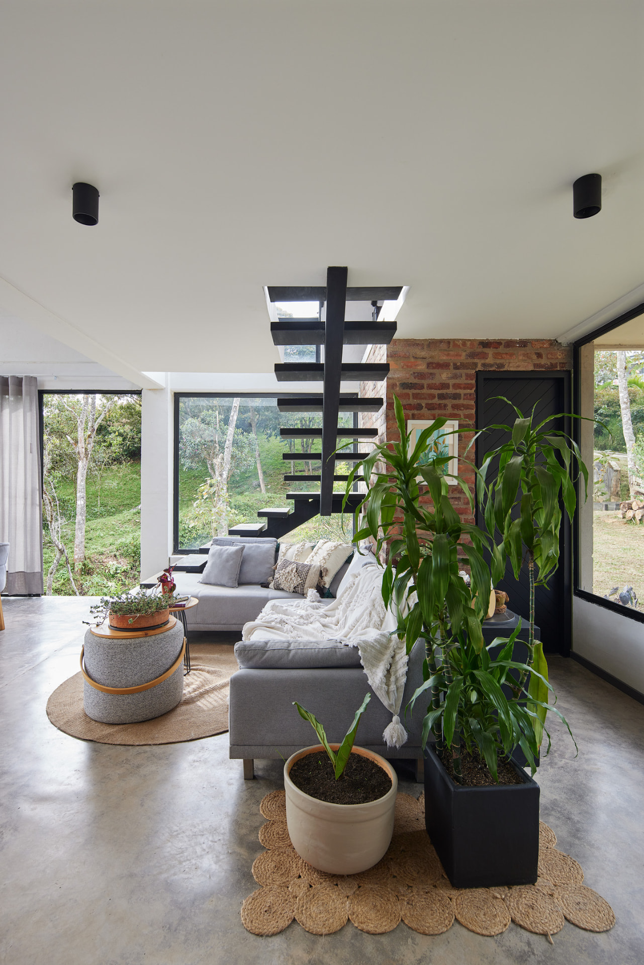 Sala de Casa Mulata con escalera flotante negra y muro de ladrillo