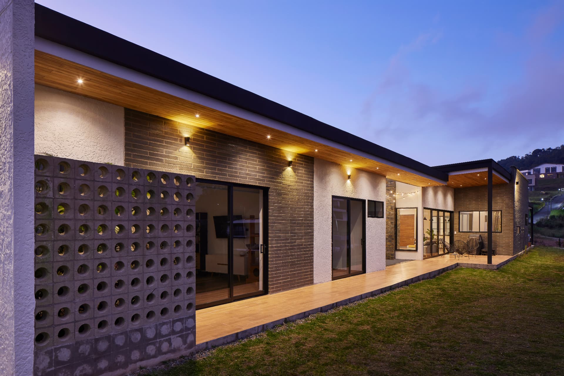 Exterior de Casa MS al atardecer con muro de celosía de concreto y deck de madera