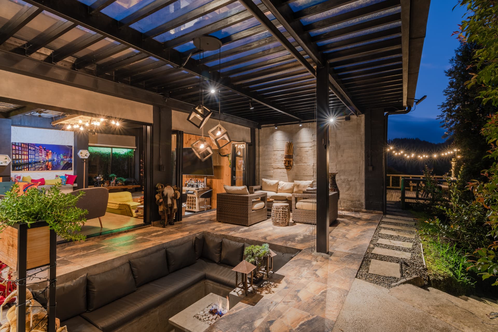Terraza de Casa Shirley al anochecer con fogata y luces cálidas