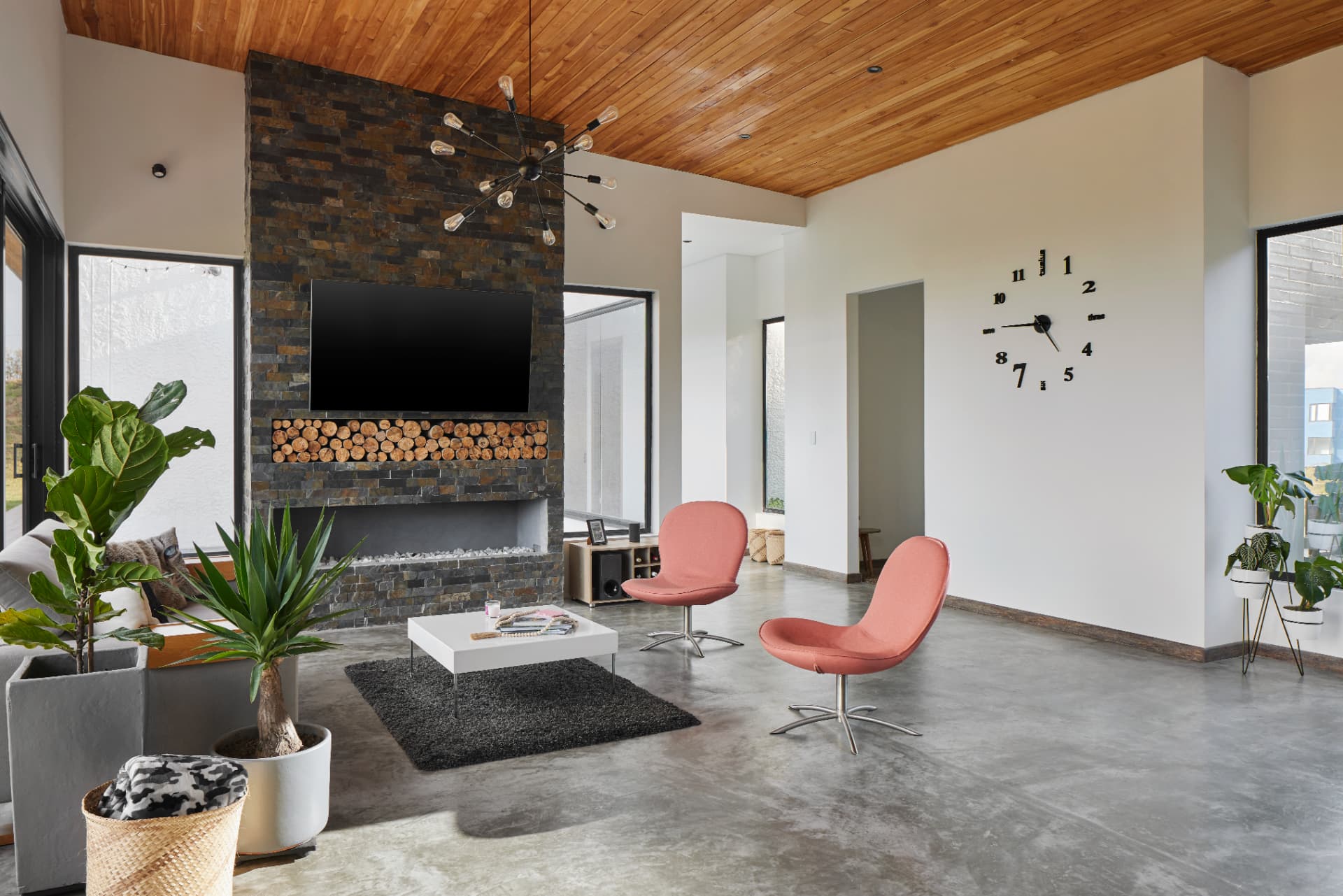 Sala de Casa MS de día con muro de piedra, techo de madera y piso de concreto pulido