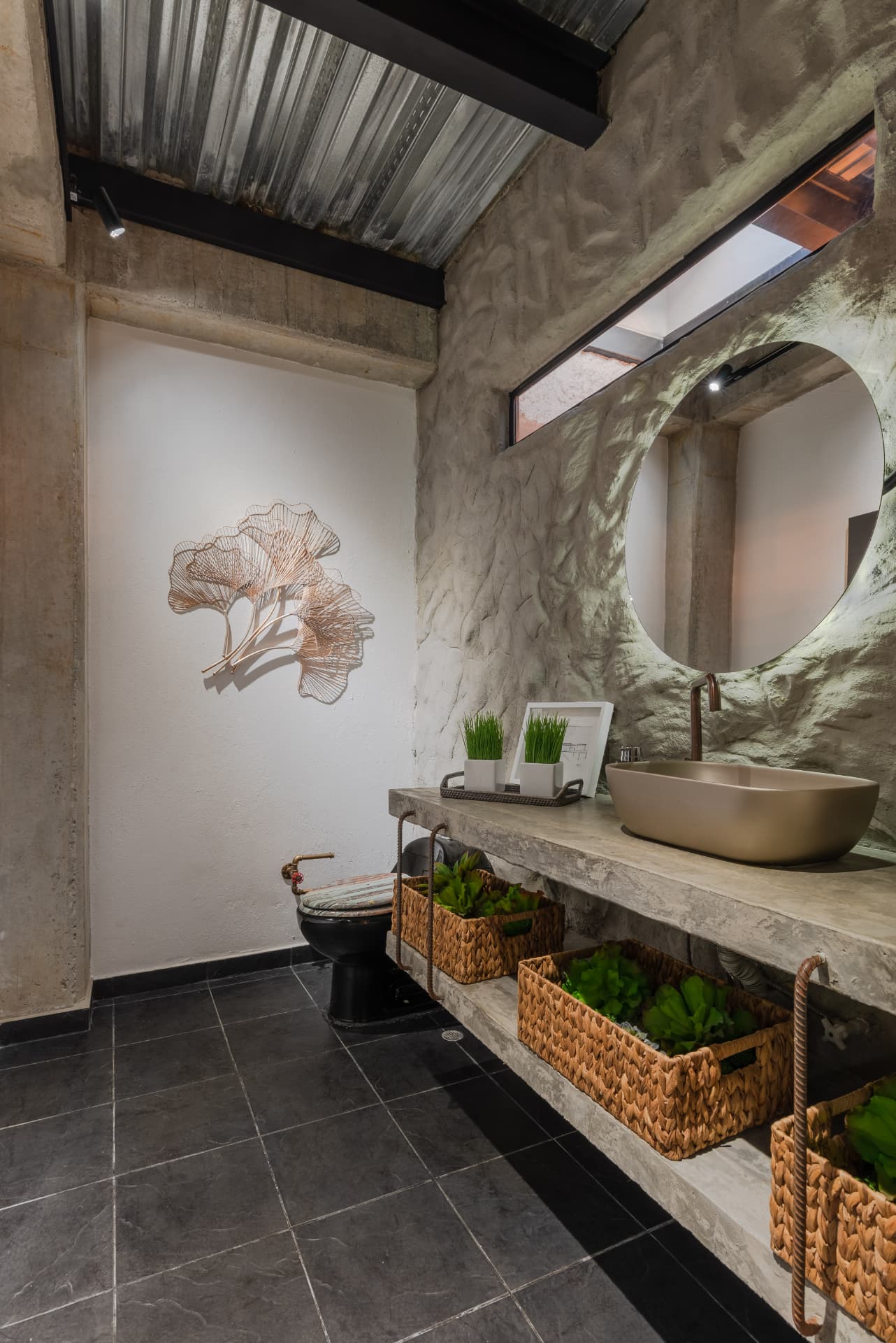 Baño de Casa Shirley con muro escultórico de concreto y espejo circular