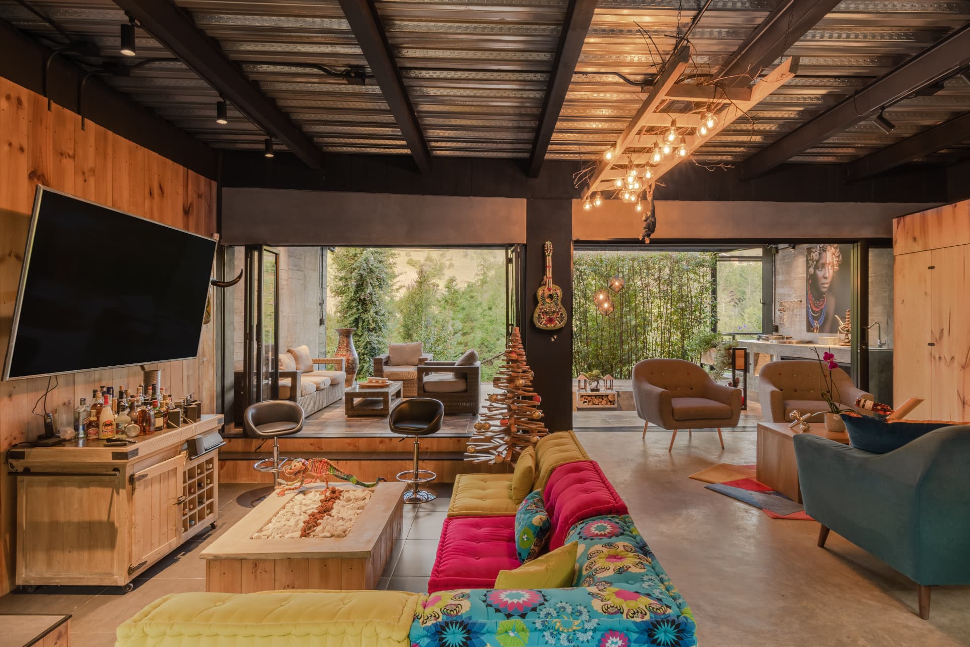 Sala de Casa Shirley con paleta vibrante, techo de lámina y vigas metálicas a la vista