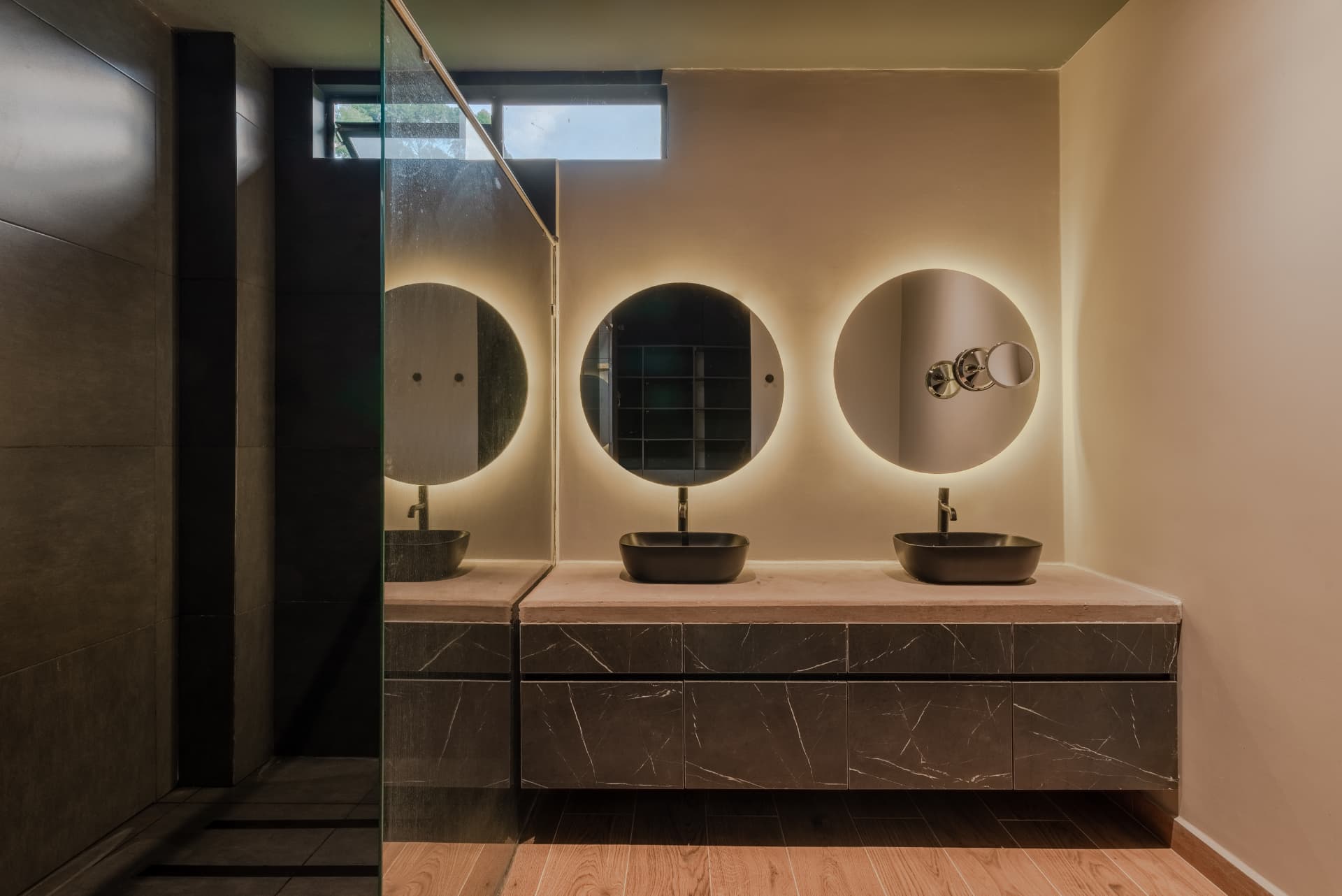 Baño doble de Pontevedra con espejos circulares iluminados y vanidad en mármol oscuro