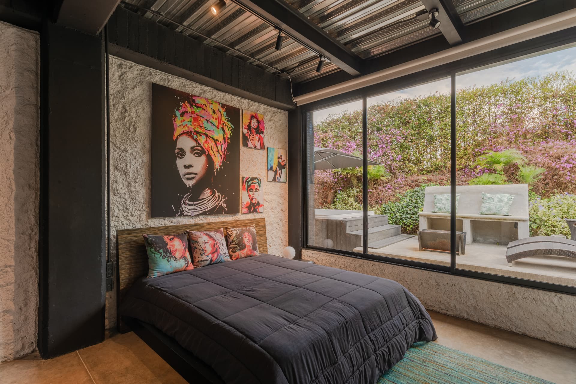 Habitación de Casa Shirley con muro de concreto, arte pop y ventanal al jardín