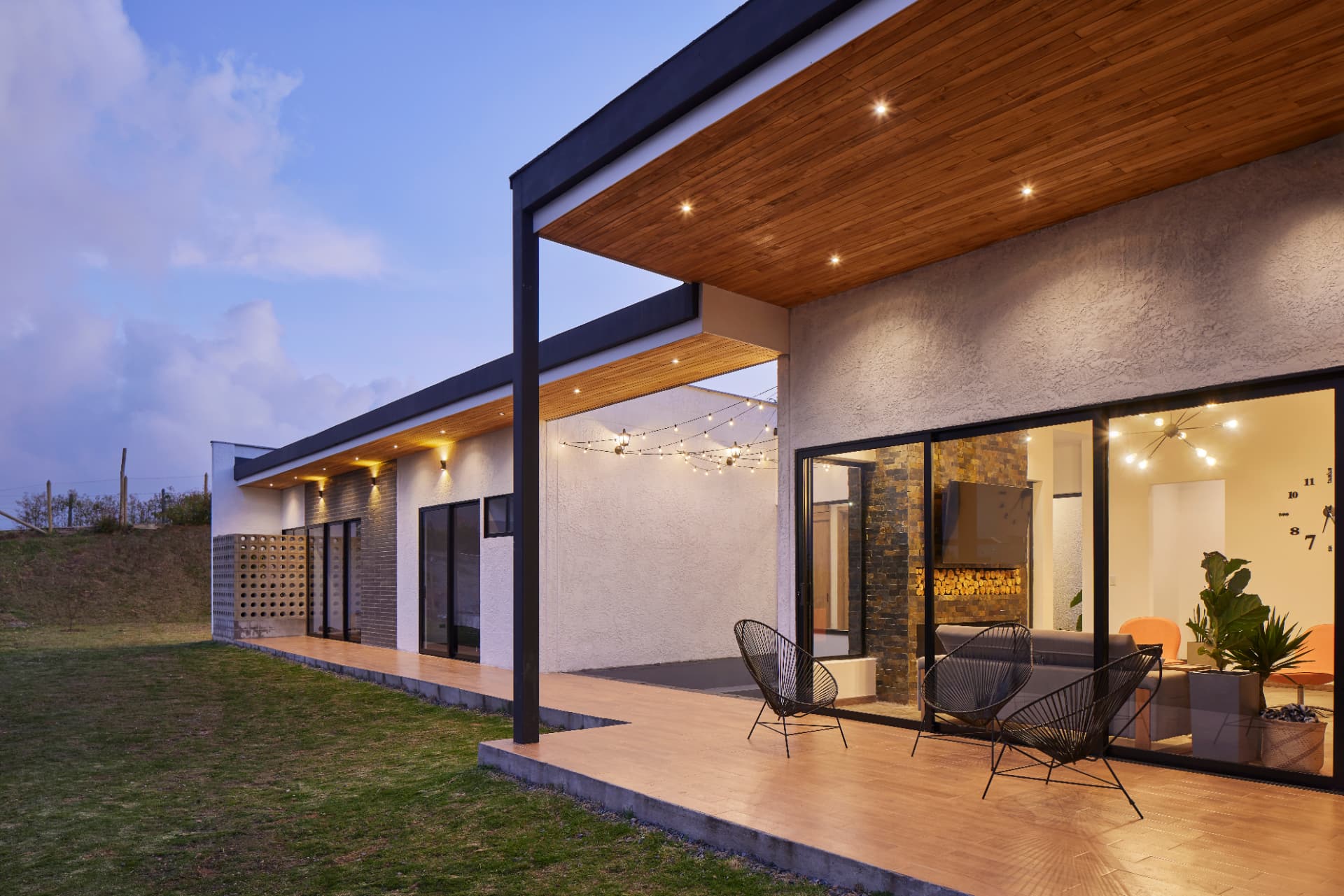 Terraza de Casa MS al anochecer con techo de madera y ventanales a la sala
