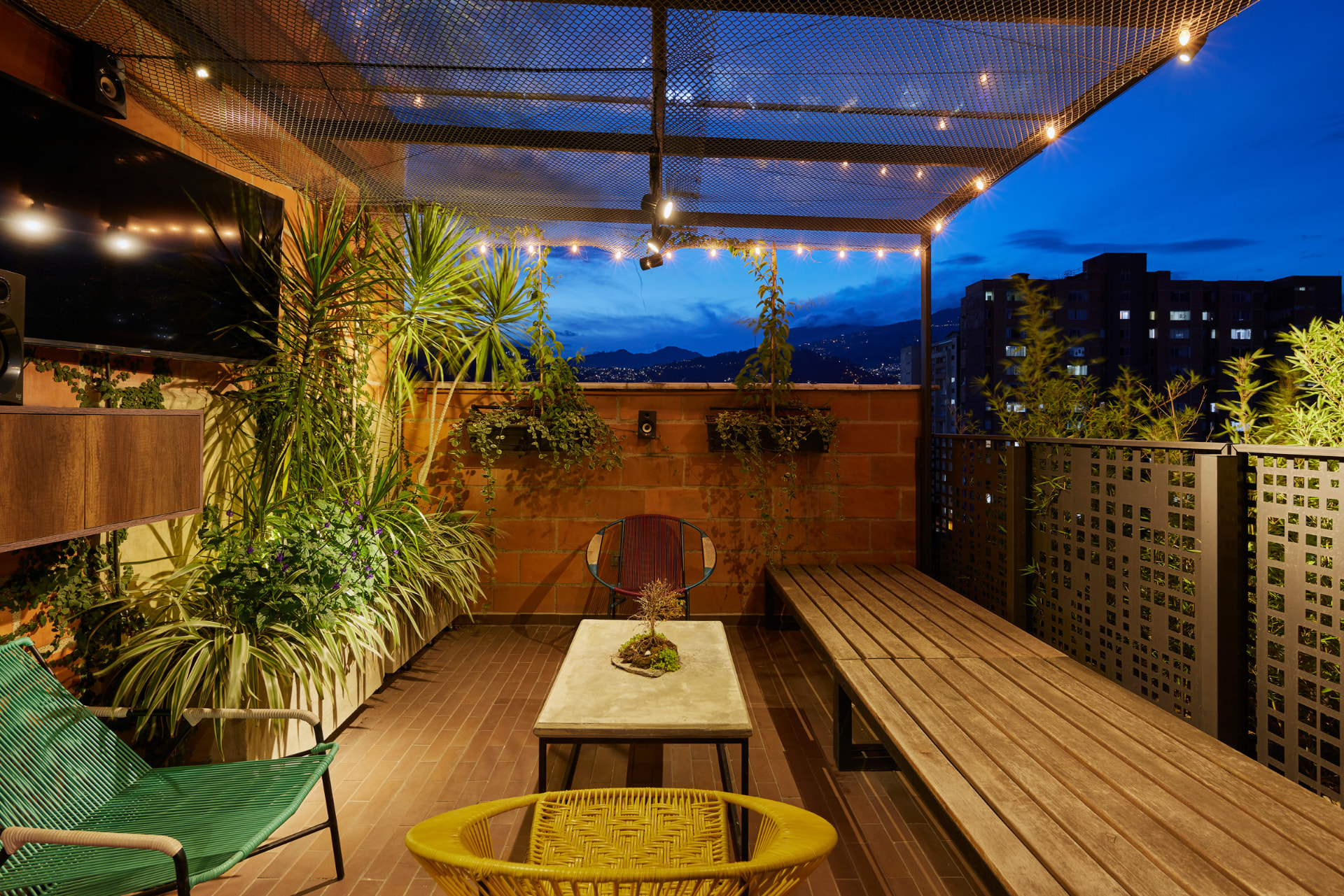 Zona de descanso de la terraza del Edificio Bianco con jardineras y luces cálidas