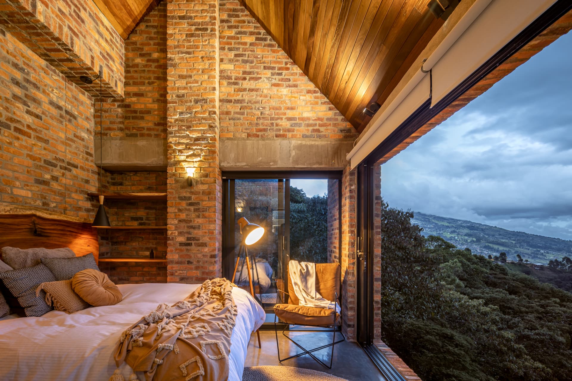 Habitación principal de Up House con muro de ladrillo y ventanal al valle